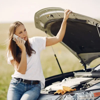 femme qui appelle une dépanneuse au bord de la route après une panne de voiture