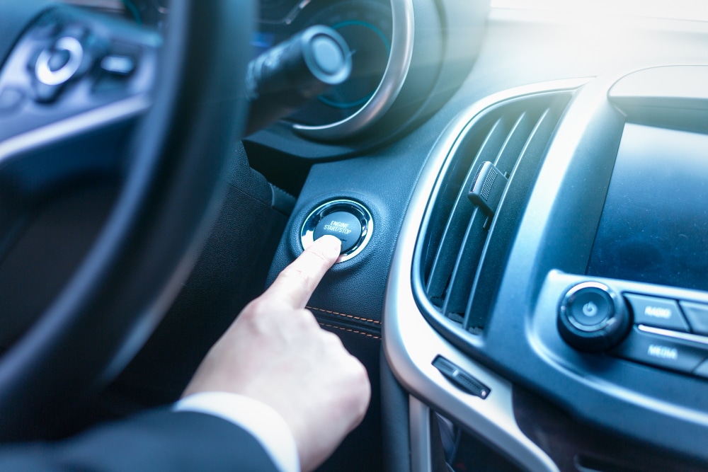 un conducteur qui appui sur le bouton de démarrage de sa voiture