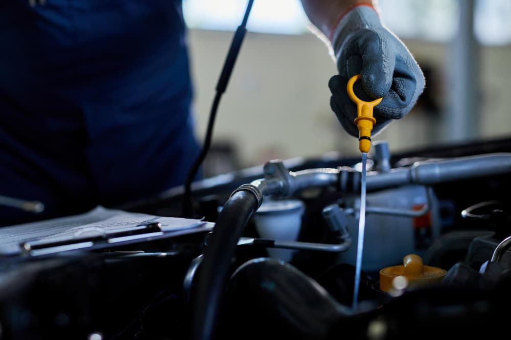 un garagiste qui contrôle le niveau d'huile du moteur sur une voiture