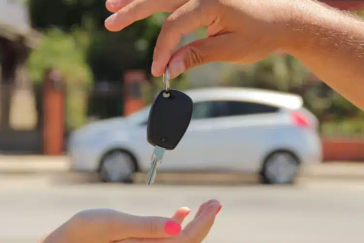 une main qui tend des clés pour une vente de voiture