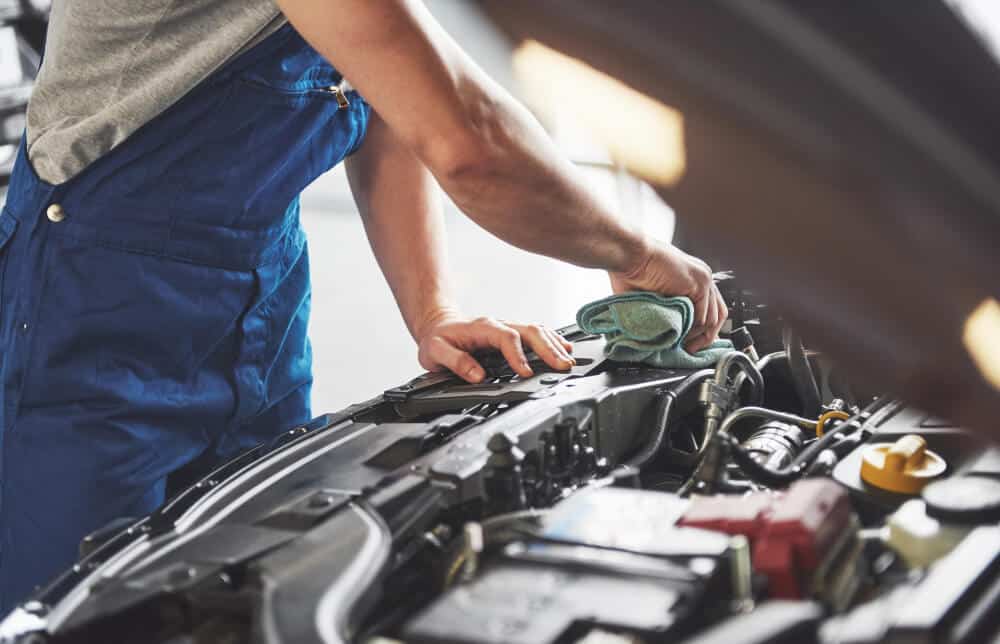 Un garagiste qui entretien le moteur d'une voiture