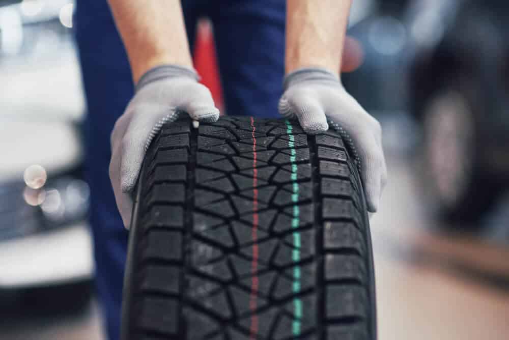 Un garagiste qui tient un pneu neuf de voiture